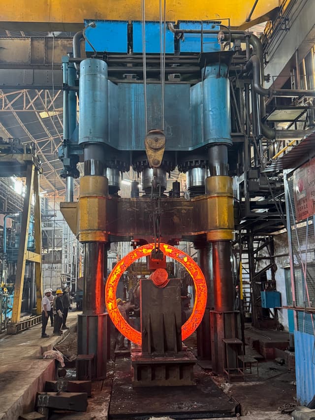 A forged ring lying flat, its rolled face still scaled from the furnace.