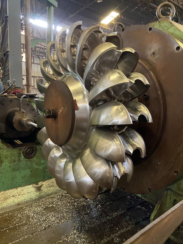 A Pelton turbine runner on the shop floor, seen across the buckets.