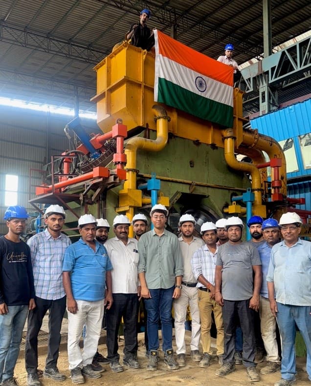 The radial forge on its first trial, an Indian flag over the press frame, with the commissioning team.