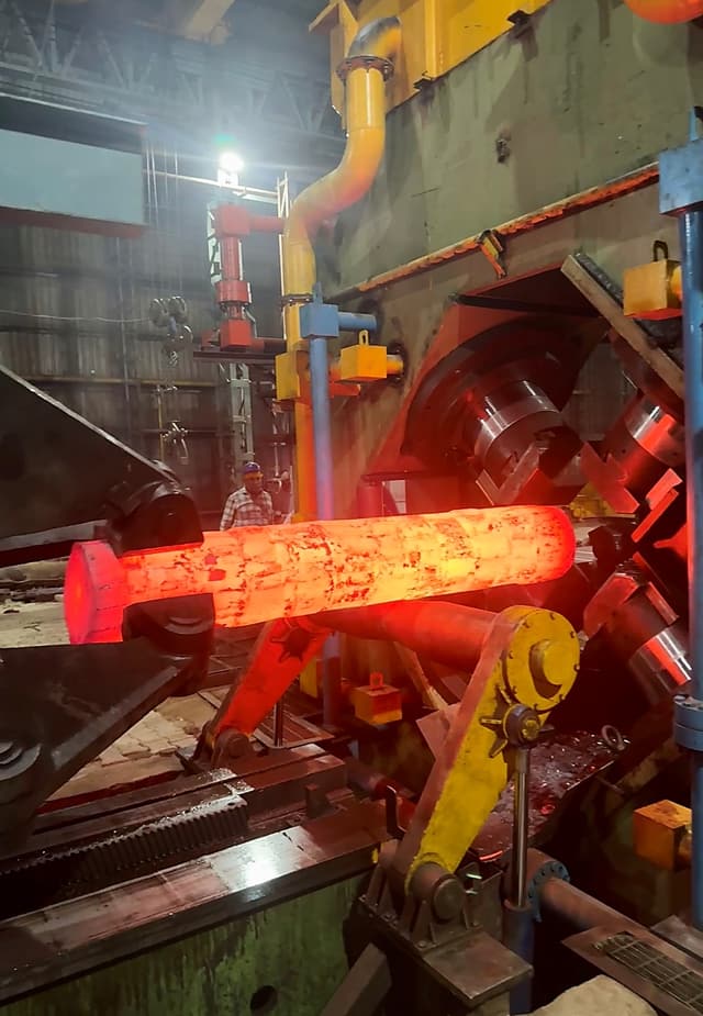 A shaft glowing along its length as it is drawn through the radial forge.
