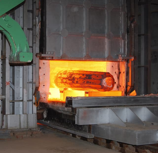 An ingot at forging heat on the hearth of a gas-fired reheating furnace.